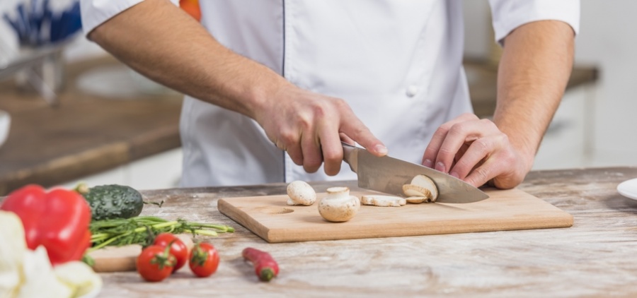Un cuisinier coupe des légumes sur son plan de travail