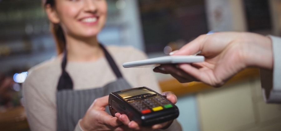 Une hôtesse de caisse fait payer un client avec un appareil à carte bancaire